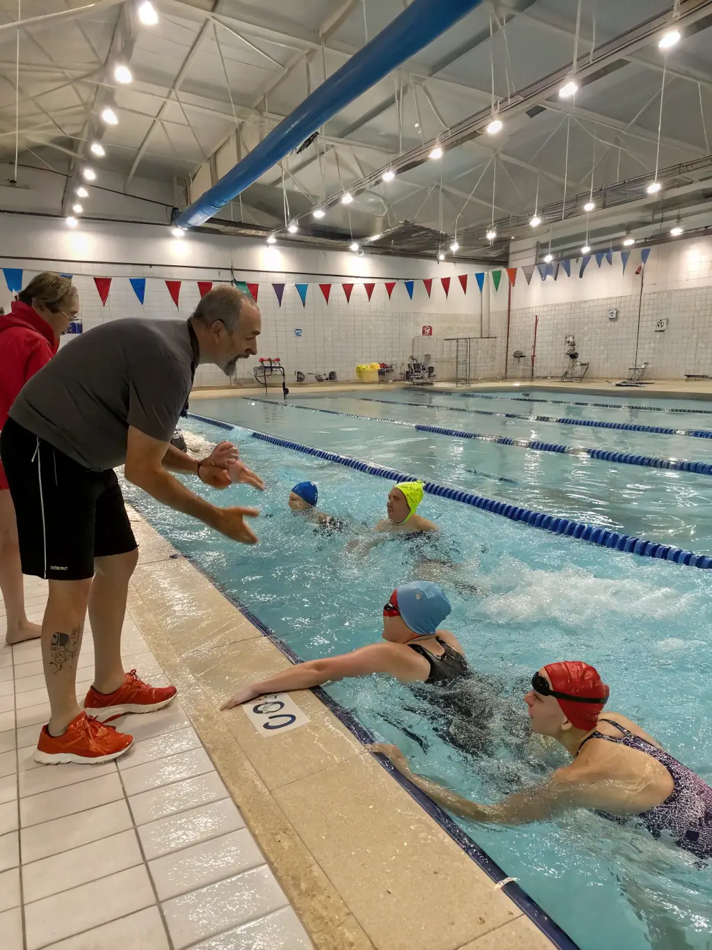 A group of children and adults practicing swimming techniques in the pool under the guidance of an instructor, showcasing the swimming lessons offered by FRANCS NAGEURS CLUB DOUAI.